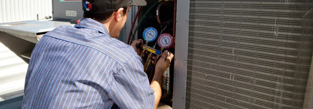 HVAC technician servicing a condenser unit in Caln