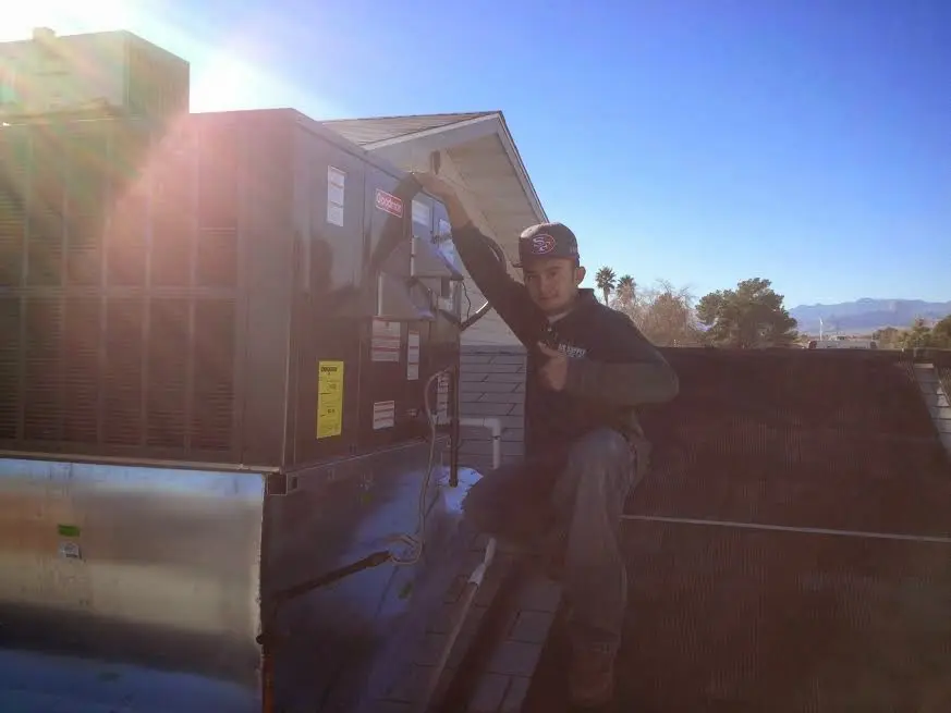 HVAC technician performing AC Tune-Up on a rooftop unit in Caln